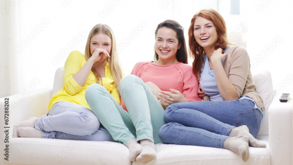 three smiling teenage girls watching tv at home three smiling teenage girls watching tv at home