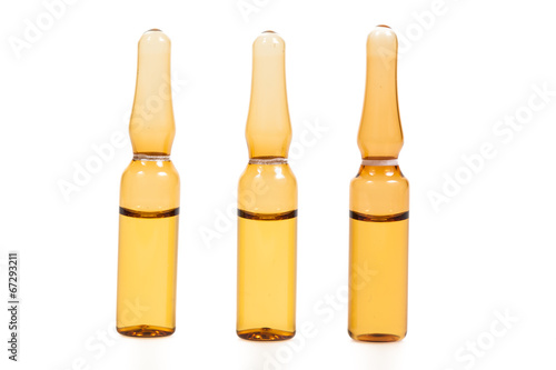 medical ampules with yellow liquid on white background