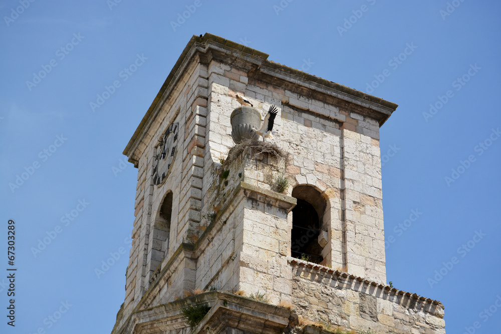 nido con dos cigüeñas en la torre de una iglesia de piedra
