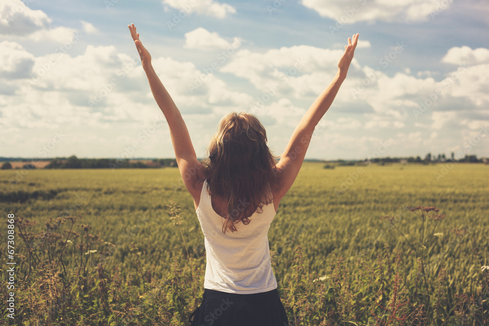 Young woman in field with her arms raised Young woman in field with her arms raised