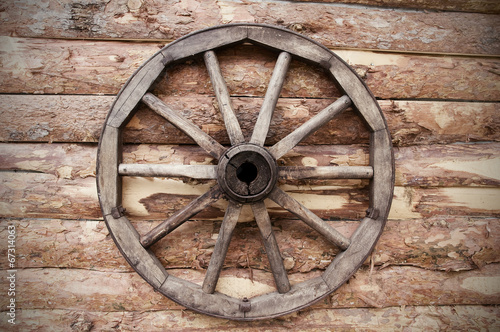 rustic wagon wheel hanging on a wall © Trifonenko Ivan