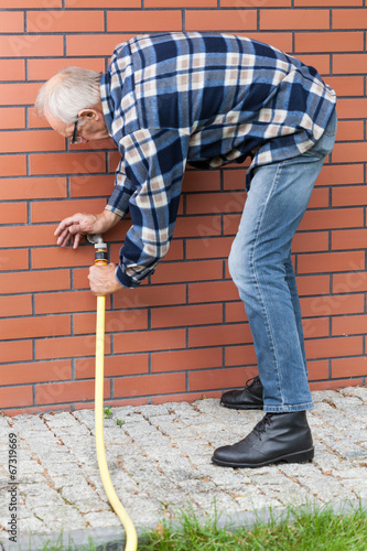 Εκτύπωση καμβά Man repairing leaky garden hose spigot