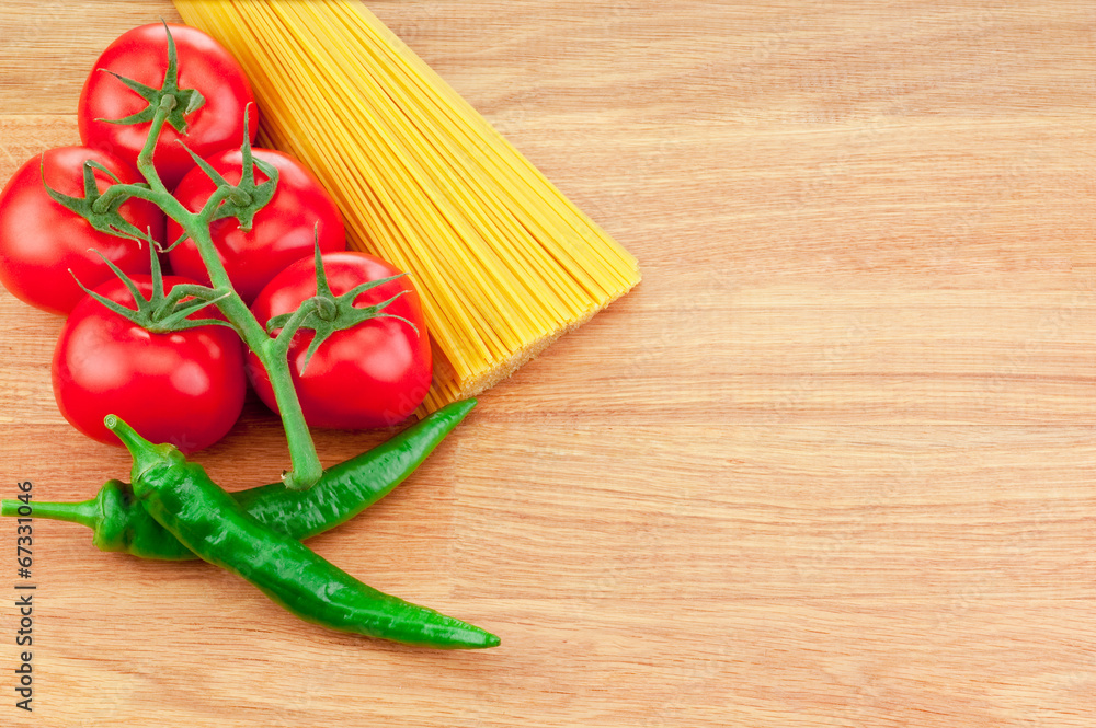 Bunch of spaghetti pasta, green hot peppers and Ripe tomatoes on Bunch of spaghetti pasta, green hot peppers and Ripe tomatoes on