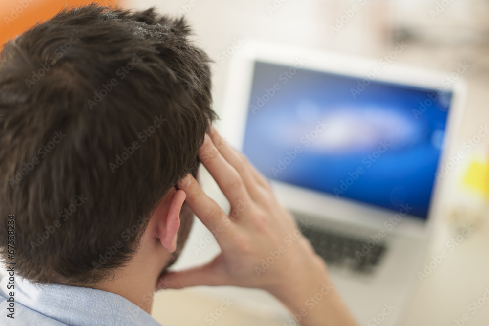 rear view of a man examining his computer's screen