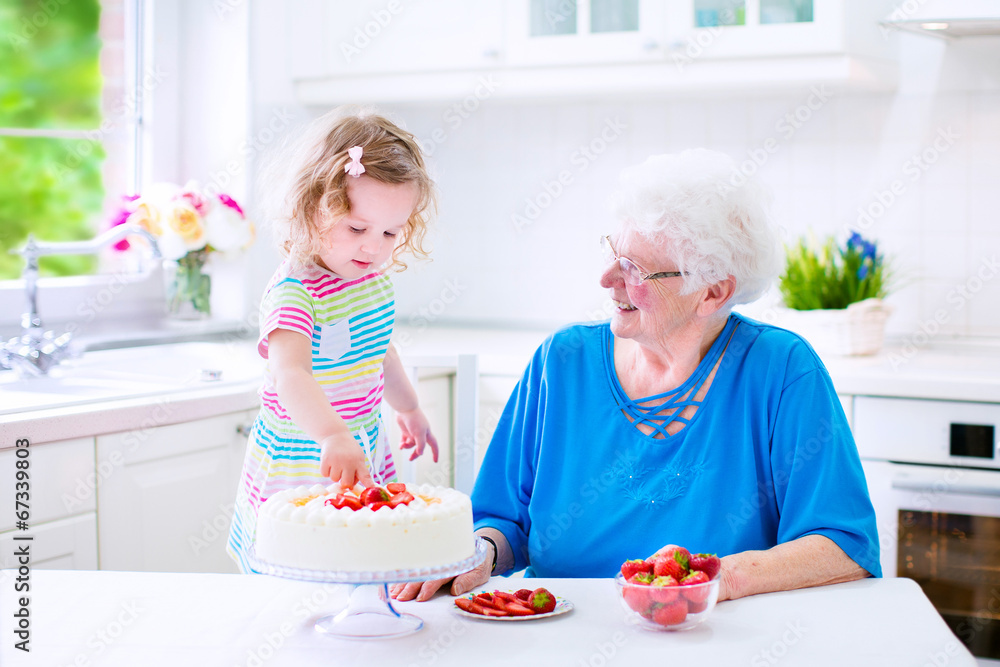 Grandmother baking cake with little granddaughter Grandmother baking cake with little granddaughter