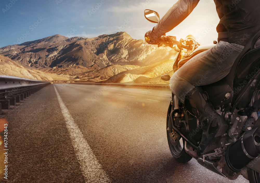 Biker riding motorcycle on an empty road at sunset - obrazy, fototapety, plakaty 