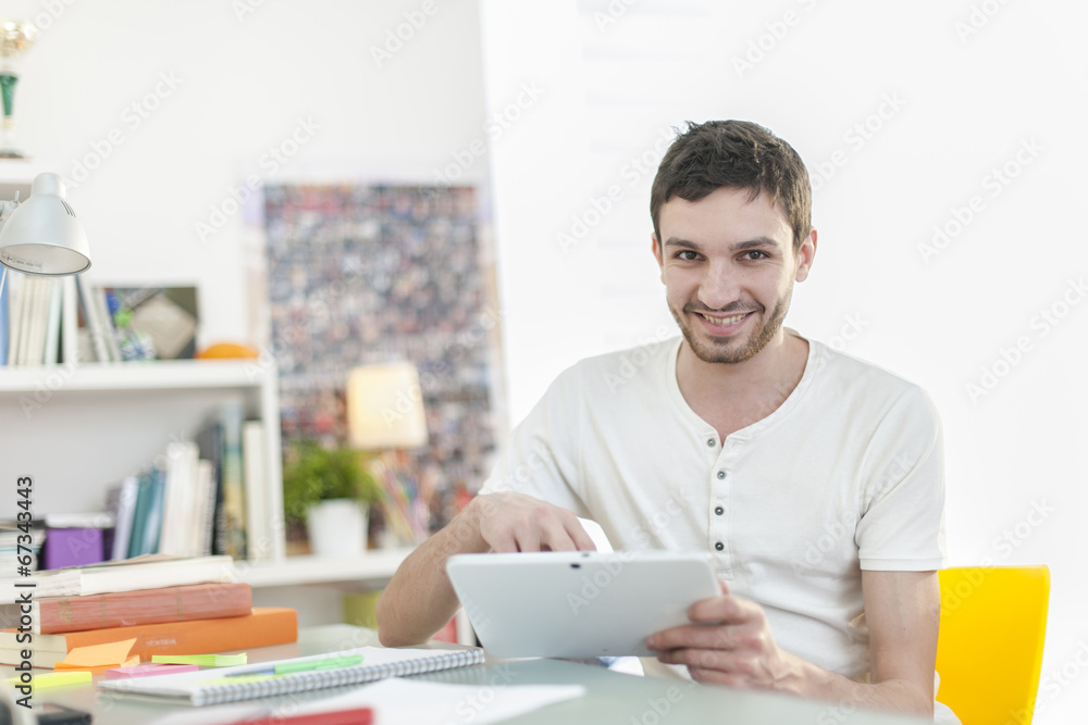 young student sitting at his desk and surfing on a digital table young student sitting at his desk and surfing on a digital table