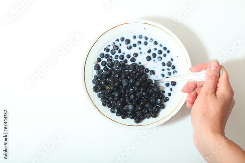 blueberries in a bowl with milk. berries stirred with a spoon