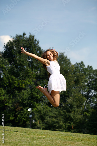 Happy young woman jumping in white dress
