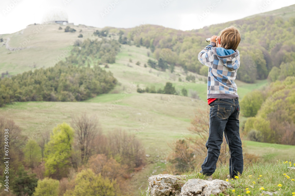 young child boy looking through binocular to the country side