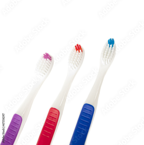 Three toothbrushes of different colors on white