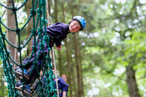 Happy boy enjoying a climbing adventure in activity park