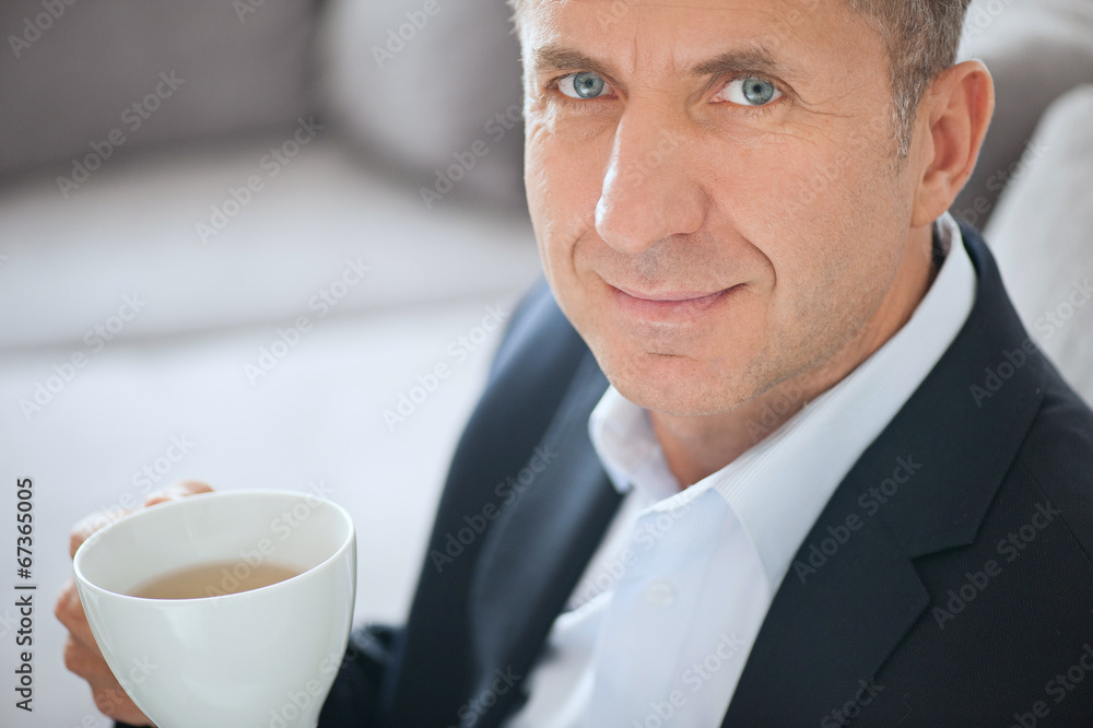 Mature businessman smiling and drinking a cup of coffee Mature businessman smiling and drinking a cup of coffee