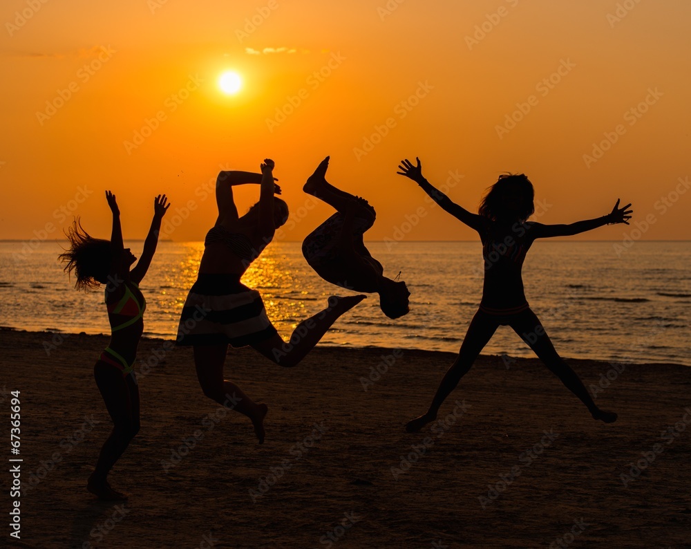 Silhouettes a young people having fun on a beach against sunset Silhouettes a young people having fun on a beach against sunset