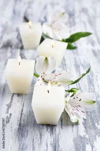 Beautiful candles with flowers on wooden background