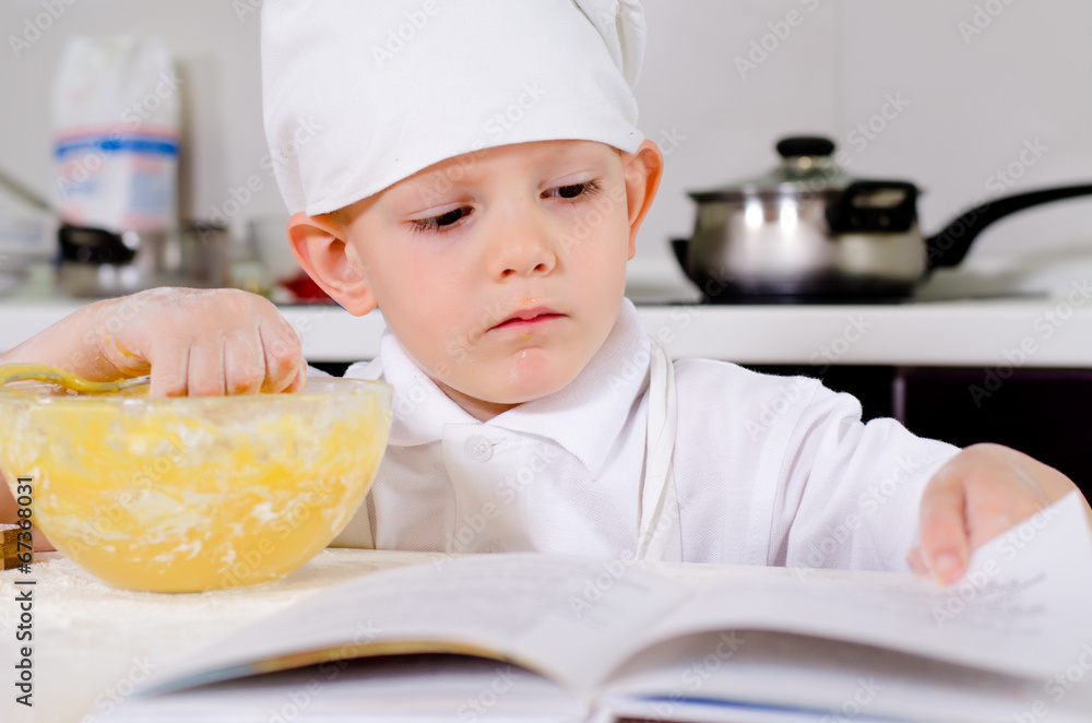 Little boy following a recipe as he bakes a cake Little boy following a recipe as he bakes a cake