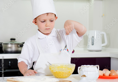 Young boy chef adding ingredients to his bowl