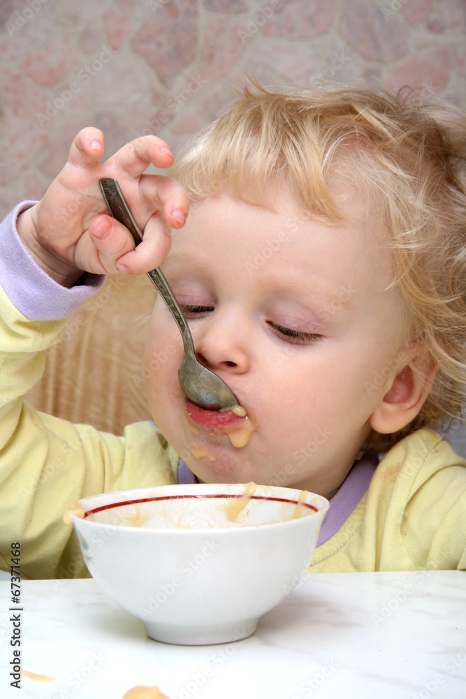 Little boy has his breakfast with good appetite Little boy has his breakfast with good appetite