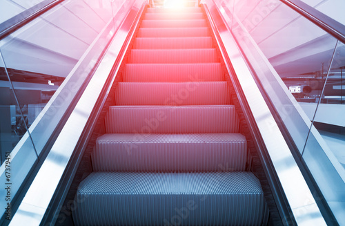 Empty escalator or moving stair. Also called stairway or staircase. Modern architecture design with step, glass for lift people up floor building i.e. shopping mall, airport, metro and subway station. photo