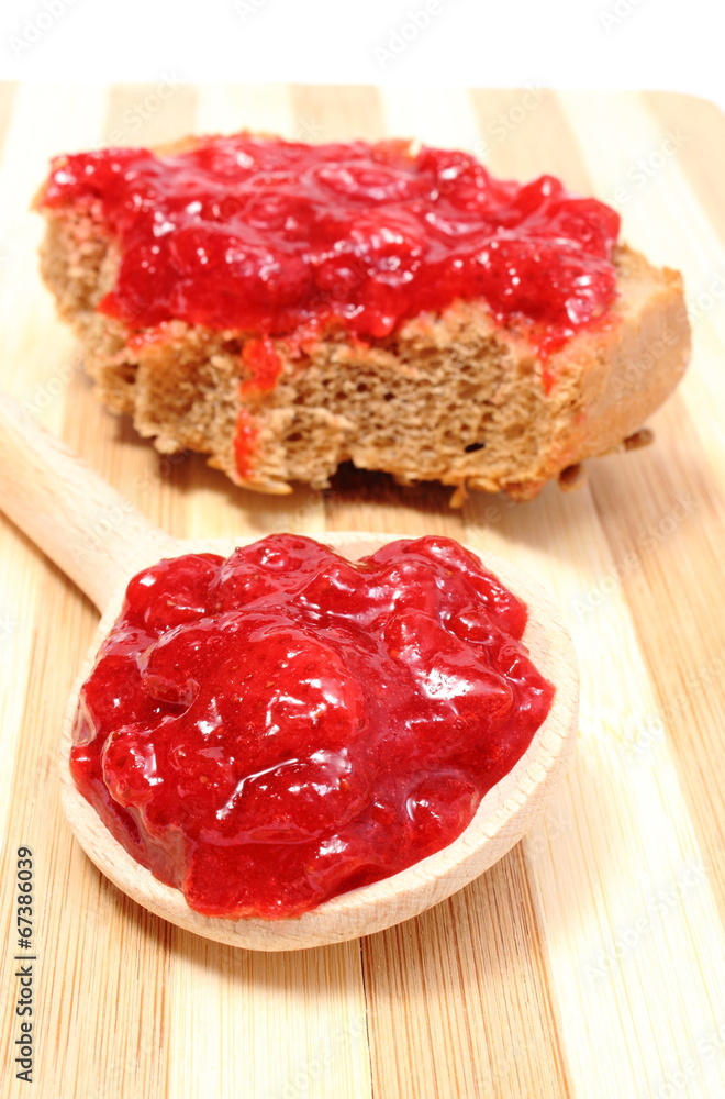 Strawberry jam on wooden spoon and whole wheat bread Strawberry jam on wooden spoon and whole wheat bread