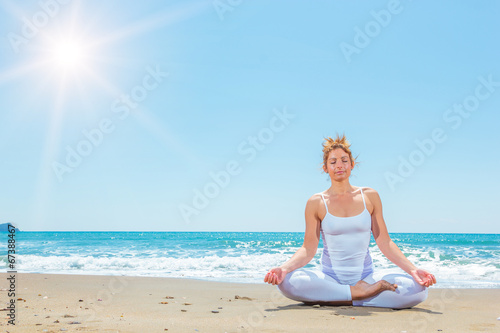 Caucasian woman practicing yoga on the beach