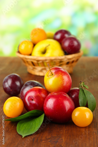 Ripe plums on wooden table on natural background