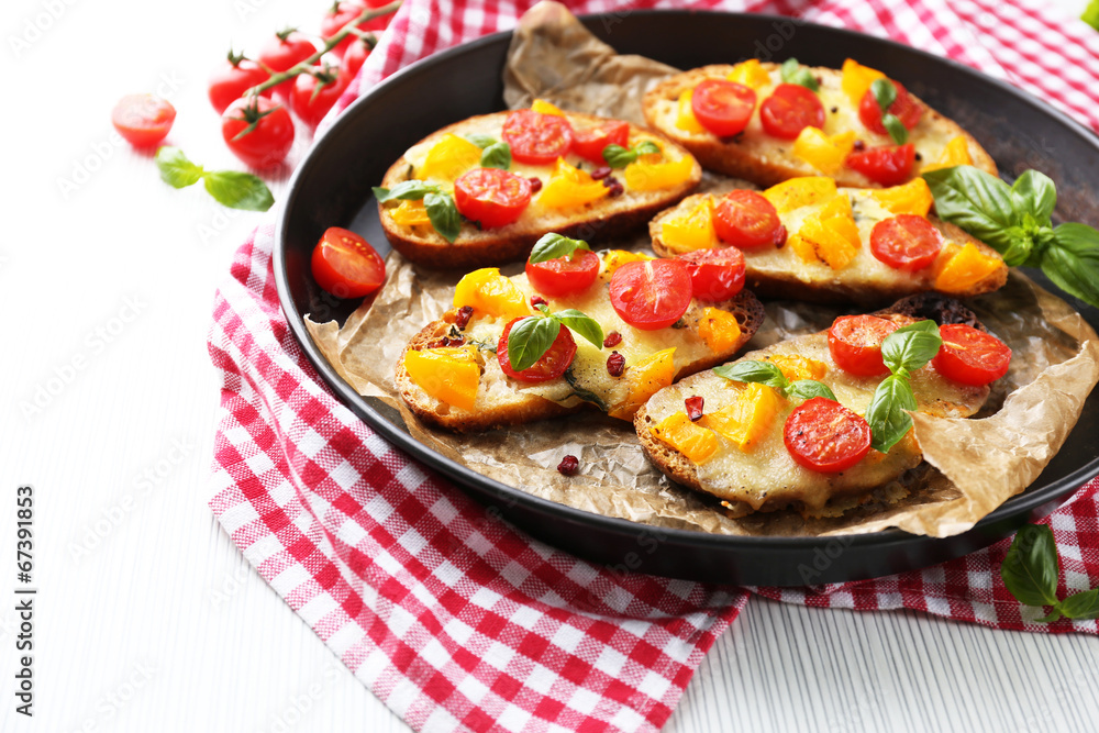 Tasty bruschetta with tomatoes in pan, on table Tasty bruschetta with tomatoes in pan, on table