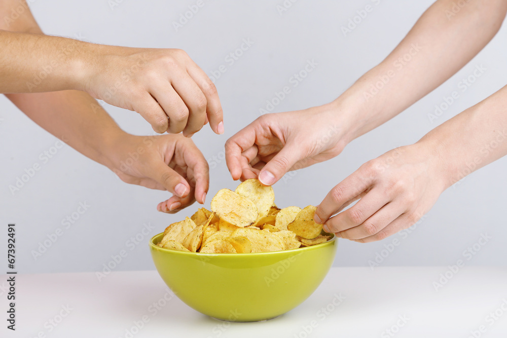 Hands of people take chips from bowl