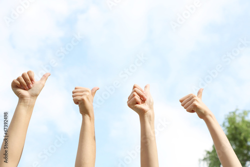 People show thumbs up on natural background