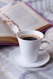 Cup of coffee on plaid with book