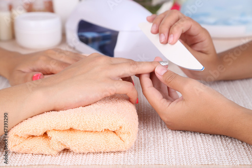 Young woman is getting manicure in beauty salon  close-up