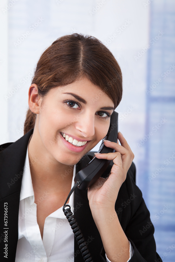 Businesswoman Using Landline Phone In Office Businesswoman Using Landline Phone In Office