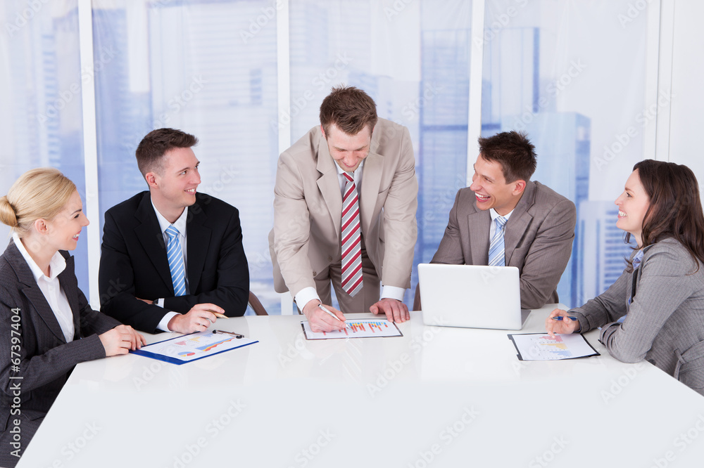 Business People Discussing Graph At Conference Table Business People Discussing Graph At Conference Table