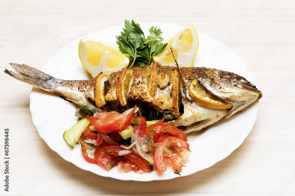 Cooked fish sea bream fish with lemon, parsley,garlic.
