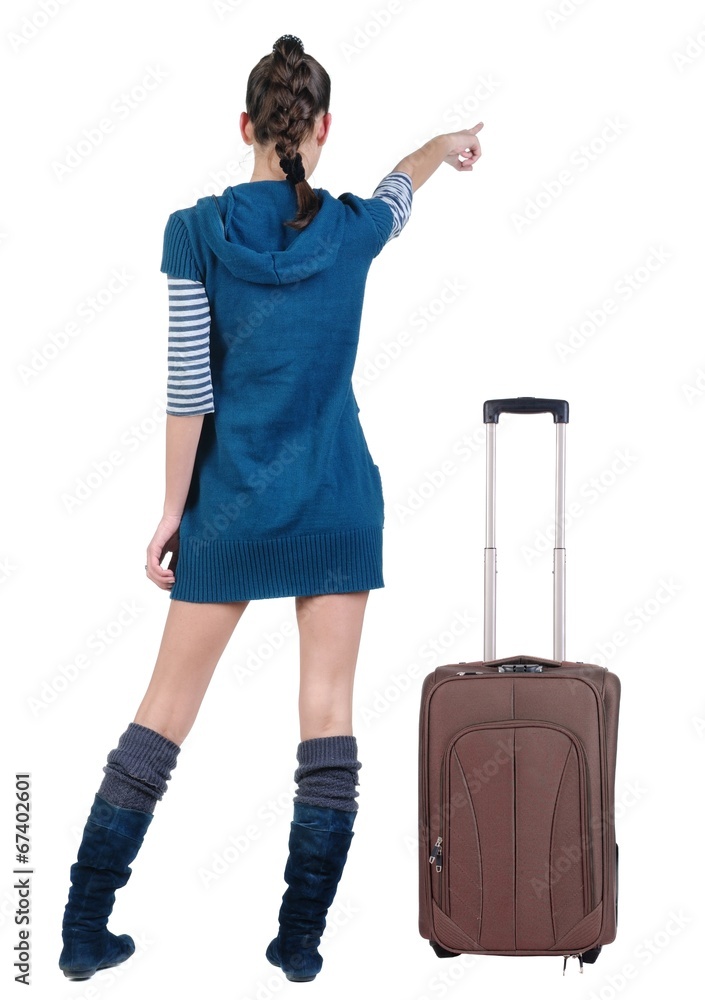 traveling young woman in dress with suitcas pointing at wall traveling young woman in dress with suitcas pointing at wall