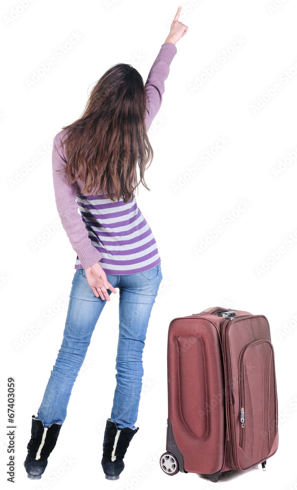 Beautiful young woman traveling with suitcas and pointing at wa Beautiful young woman traveling with suitcas and pointing at wa