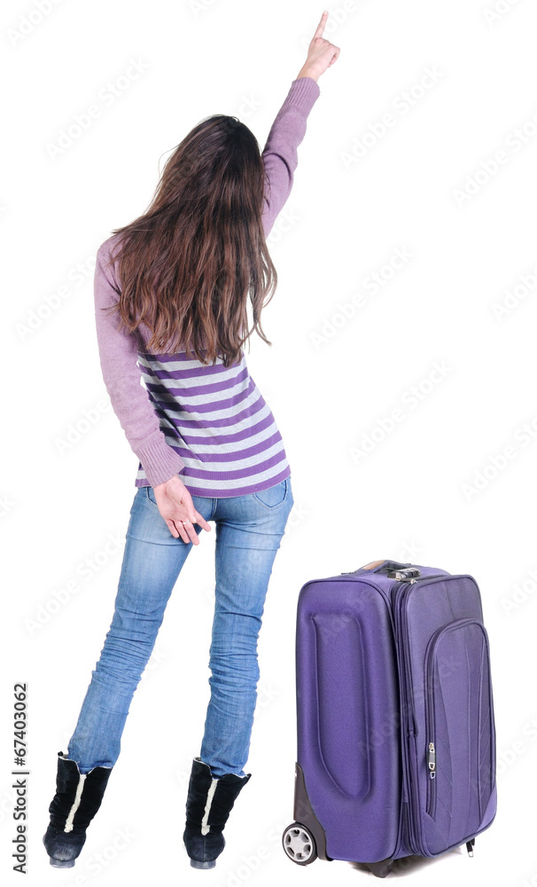 Beautiful young woman traveling with suitcas and pointing at wa Beautiful young woman traveling with suitcas and pointing at wa