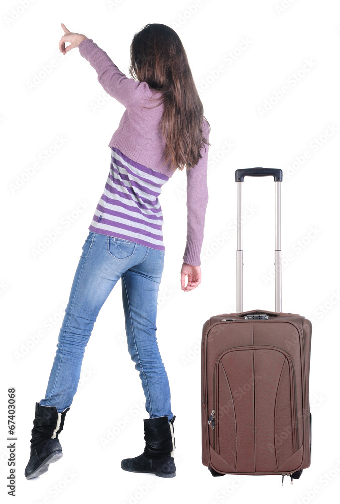 Beautiful young woman traveling with suitcas and pointing at wa Beautiful young woman traveling with suitcas and pointing at wa