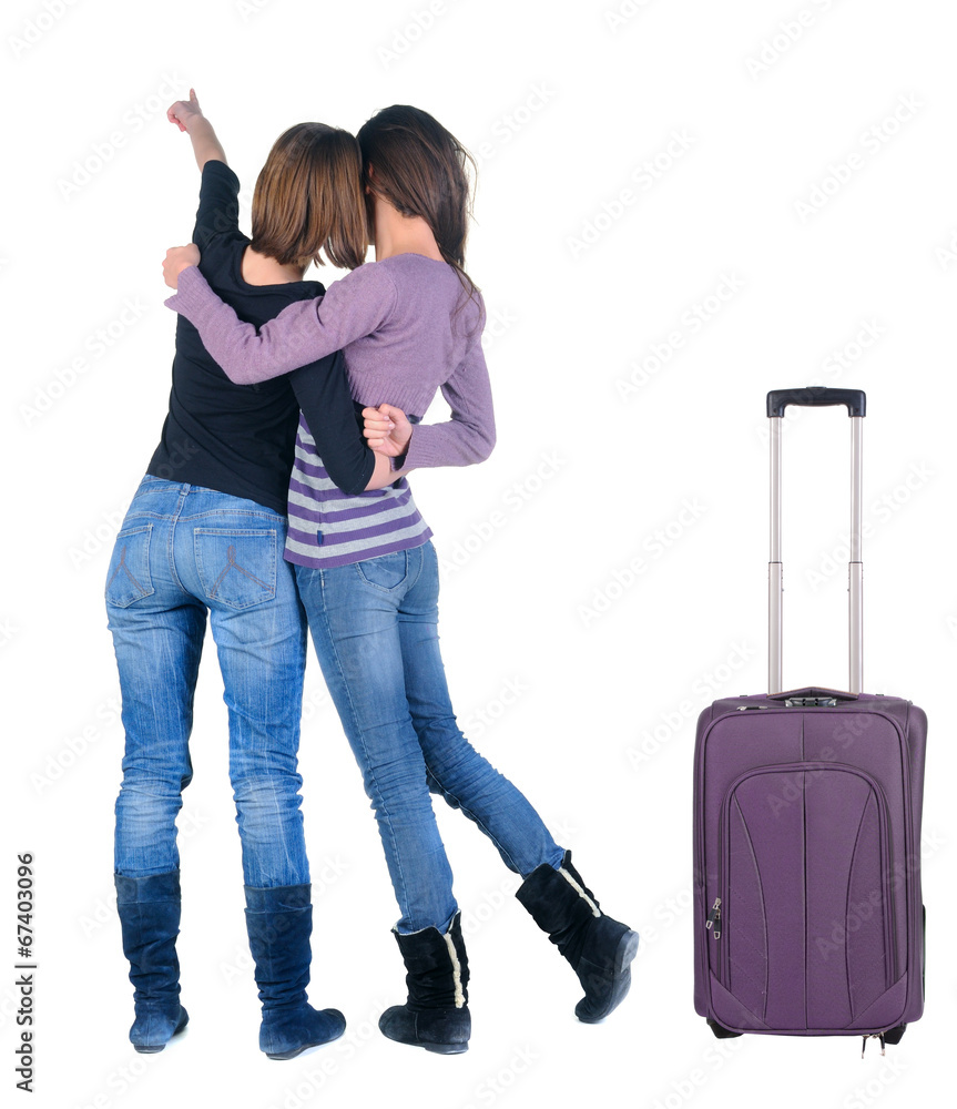 Two women traveling with suitcas and pointing at wall. Two women traveling with suitcas and pointing at wall.