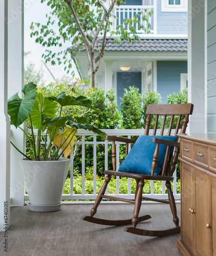 wooden rocking chair on front porch with pillow
