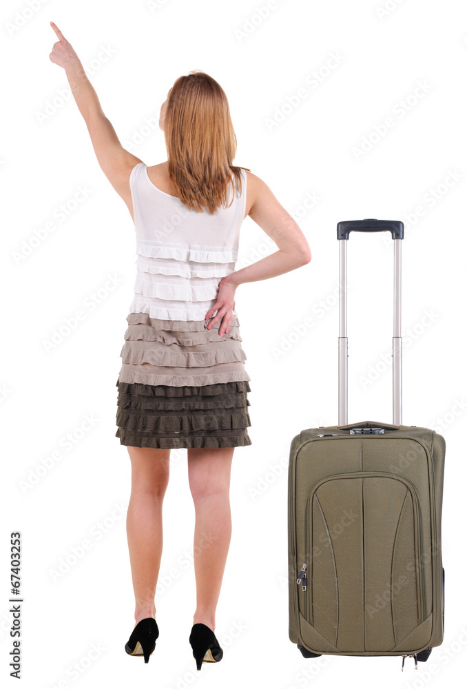 Beautiful young woman in dress traveling with suitcas and pointi Beautiful young woman in dress traveling with suitcas and pointi