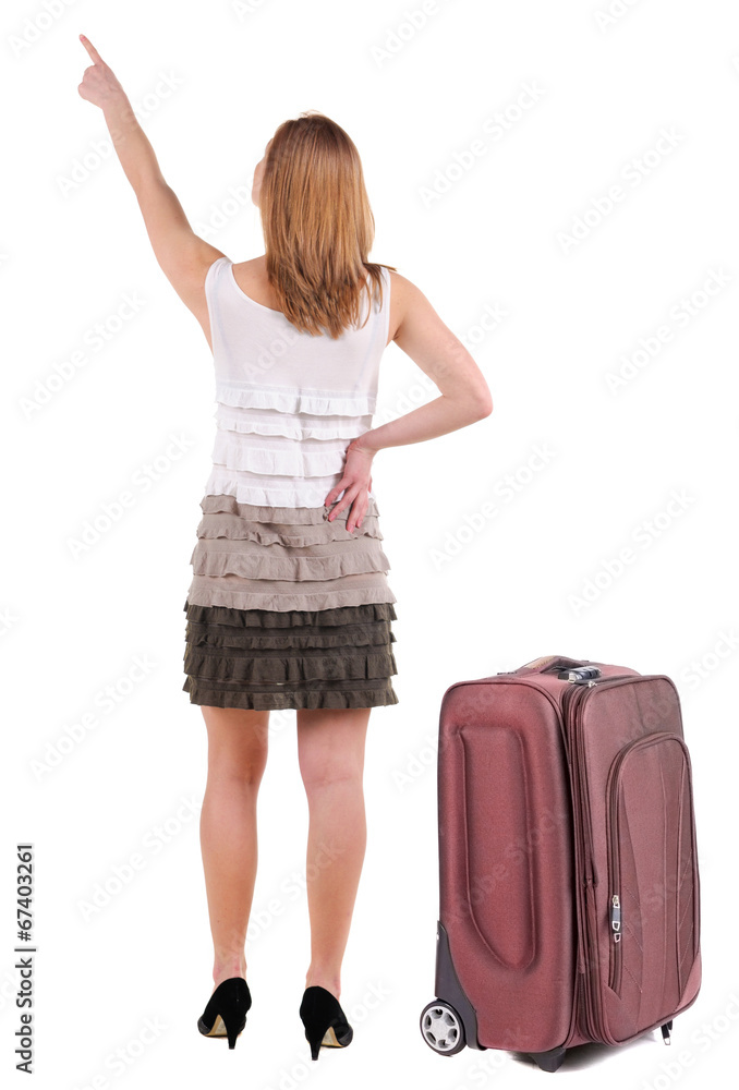 Beautiful young woman in dress traveling with suitcas and pointi Beautiful young woman in dress traveling with suitcas and pointi