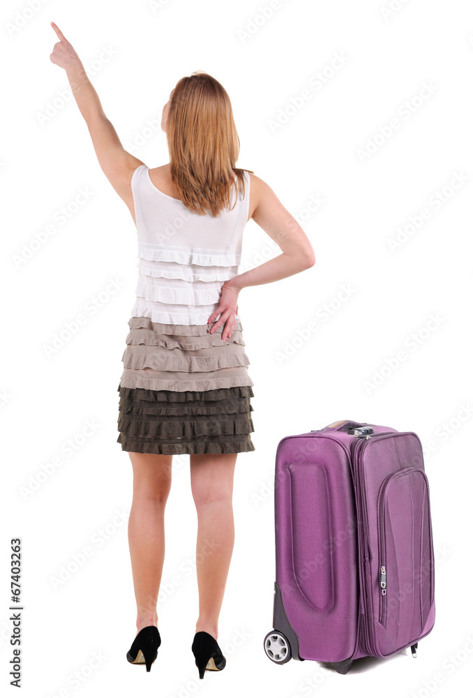 Beautiful young woman in dress traveling with suitcas and pointi Beautiful young woman in dress traveling with suitcas and pointi