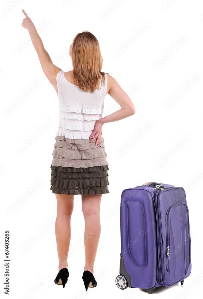 Beautiful young woman in dress traveling with suitcas and pointi Beautiful young woman in dress traveling with suitcas and pointi