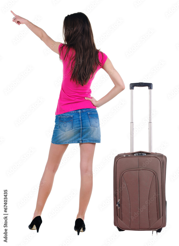 Beautiful young woman in dress traveling with suitcas and pointi Beautiful young woman in dress traveling with suitcas and pointi