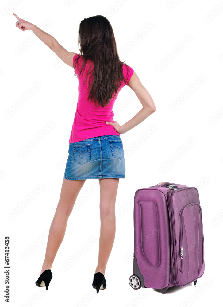 Beautiful young woman in dress traveling with suitcas and pointi Beautiful young woman in dress traveling with suitcas and pointi
