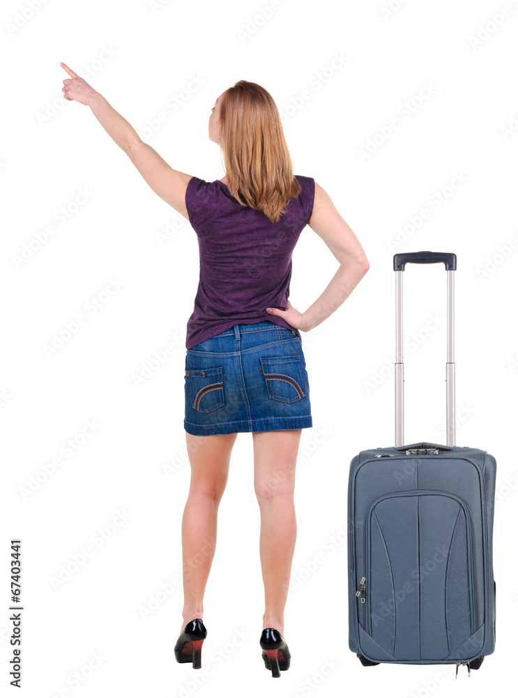 Beautiful young woman in dress traveling with suitcas and point Beautiful young woman in dress traveling with suitcas and point