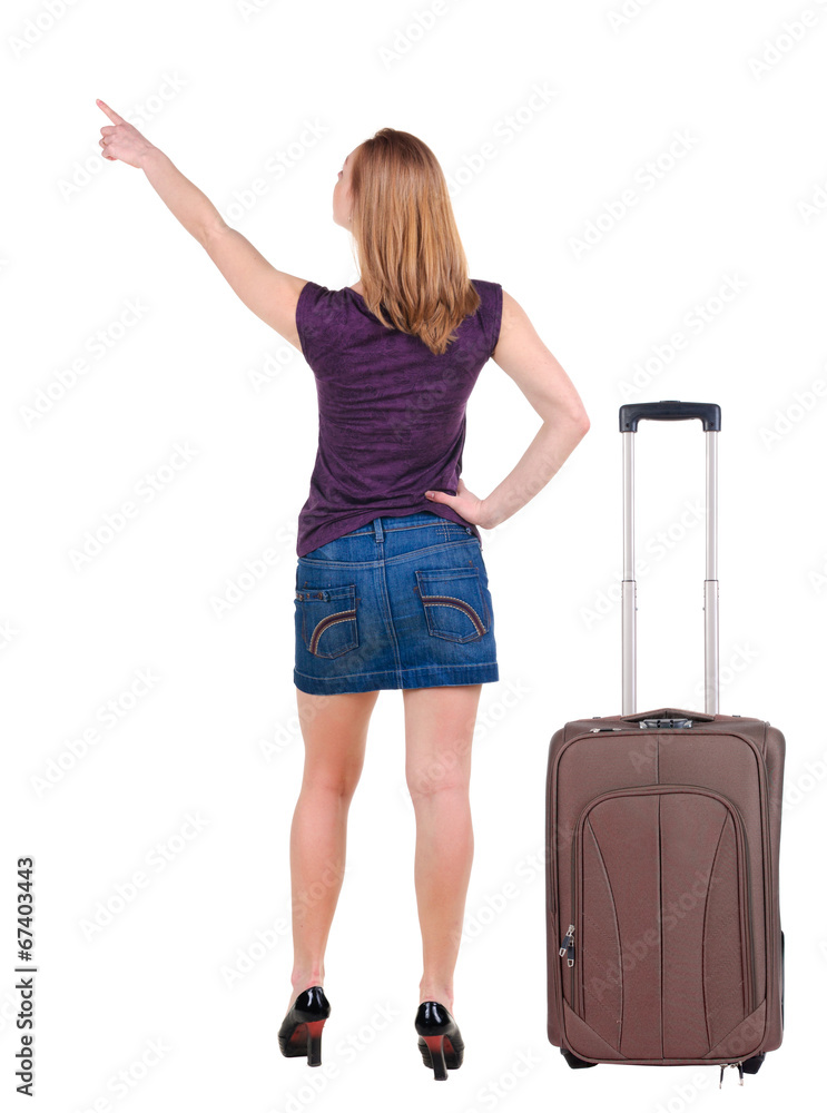 Beautiful young woman in dress traveling with suitcas and point Beautiful young woman in dress traveling with suitcas and point