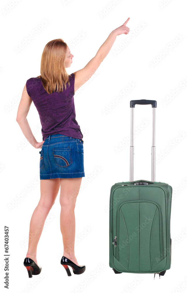 Beautiful young woman in dress traveling with suitcas and point Beautiful young woman in dress traveling with suitcas and point