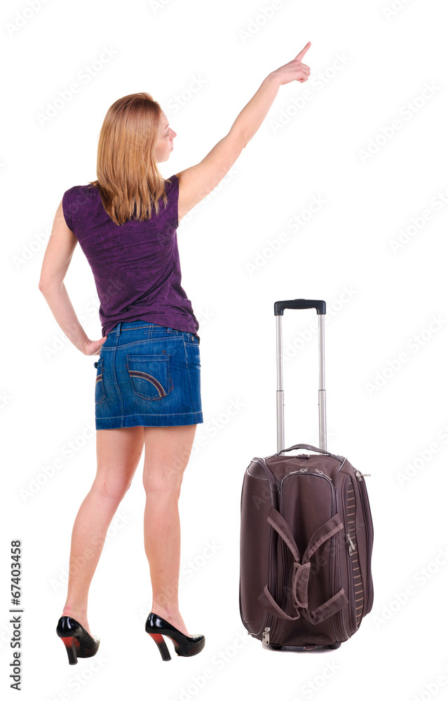 Beautiful young woman in dress traveling with suitcas and point Beautiful young woman in dress traveling with suitcas and point